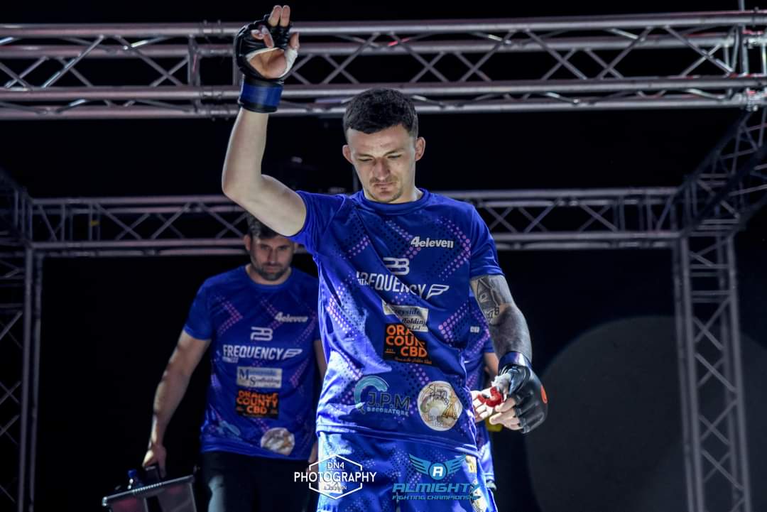 Fighter walking out in a royal blue custom 4 Eleven tee covered in sponsor logos