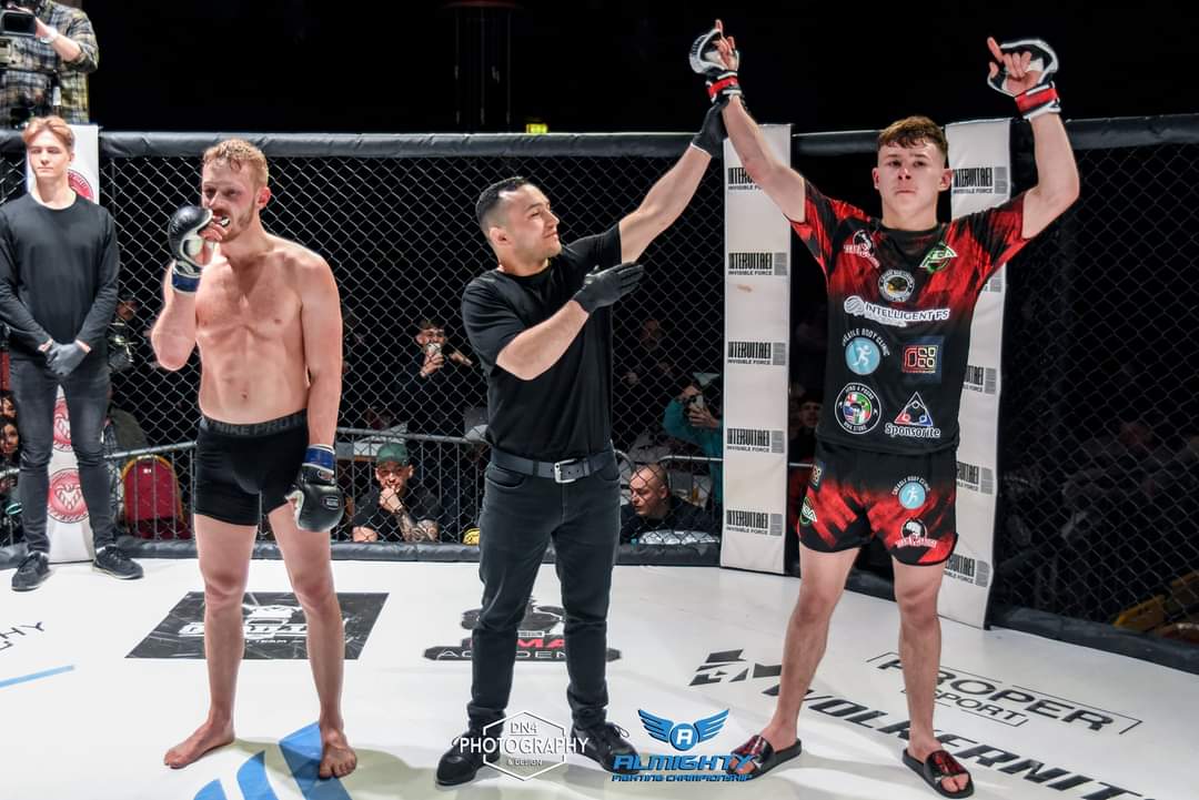 Fighter in red and black custom 4 Eleven kit having his hand raised after a win